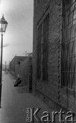 Lata 50. lub 60., Warszawa, Polska.
Ulica Grzybowska, kobieta siedząca pod murem posesji nr 23 - ujęcie w kierunku wschodnim. Odbudowany fragment domu na posesji nr 25 (z prawej). 
Fot. Stanisław Pieniążek, zbiory Ośrodka KARTA