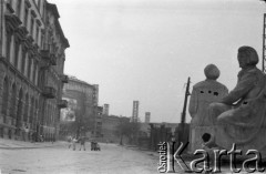 Lata 50. lub 60., Warszawa, Polska.
Ulica Aleksandra Fredry – widok w kierunku północno-wschodnim. Rzeźby Adama Mickiewicza i Mikołaja Kopernika ( z prawej). Od lewej kolejno budynki na ulicy Aleksandra Fredry 8 i 6, dalej Teatr Wielki i blok przy ulicy Moliera 2/4/6.
Fot. NN, kolekcja Ireny Jarosińskiej, zbiory Ośrodka KARTA