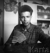 Lata 50., Warszawa, Polska.
Młody mężczyzna z kartami do gry.
Fot. Irena Jarosińska, zbiory Ośrodka KARTA