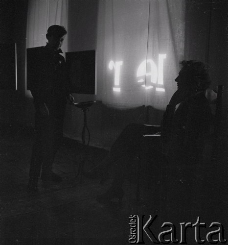 Marzec-kwiecień 1961, Warszawa, Polska.
Galeria Krzywe Koło po zmroku. Na wystawie malarstwa Barbary Pniewskiej w Galerii Krzywe Koło m.in. (po prawej) Marek Jarosiński, syn Ireny Jarosińskiej.
Fot. Irena Jarosińska, zbiory Ośrodka KARTA