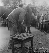 1958, Polska.
Z okazji 400 rocznicy założenia Poczty Polskiej, trasą Kielce-Wrocław przejechał zabytkowy dyliżans pocztowy. Nz. podkuwanie konia.
Fot. Irena Jarosińska, zbiory Ośrodka KARTA