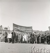 1.05.1954, Starogard Gdański, Polska
Pochód pierwszomajowy - uczestnicy niosą transparent z napisem „Chłopi, chłopki! Rozwijajcie hodowlę, rozszerzajcie kontraktację, wypełniajcie z honorem obowiązki wobec ojczyzny”. W głębi widać orkiestrę.
Fot. Irena Jarosińska, zbiory Ośrodka KARTA
