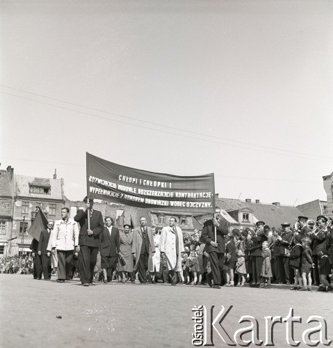 1.05.1954, Starogard Gdański, Polska
Pochód pierwszomajowy - uczestnicy niosą transparent z napisem „Chłopi, chłopki! Rozwijajcie hodowlę, rozszerzajcie kontraktację, wypełniajcie z honorem obowiązki wobec ojczyzny”. W głębi widać orkiestrę.
Fot. Irena Jarosińska, zbiory Ośrodka KARTA