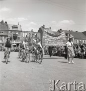 1.05.1954, Starogard Gdański, Polska
Kolarze w pochodzie pierwszomajowym, obok widoczny transparent z napisem: „Aby móc realizować IV rok planu 6 letniego i przyśpieszyć budowę socjalizmu w naszym kraju zgłaszamy się ochotniczo do brygady rolnej”.
Fot. Irena Jarosińska, zbiory Ośrodka KARTA