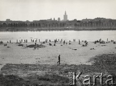 lata 50-te, Warszawa, Polska.
Widok na lewobrzeżną część Warszawy z prawego brzegu Wisły. Na pierwszym planie Sławomir Mrożek podczas spaceru po plaży.
Fot. Irena Jarosińska, zbiory Ośrodka KARTA.