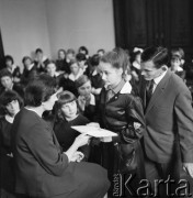 1963-1966, Szczecin, Polska.
Lekcja języka polskiego w Technikum Ekonomicznym. Nauczycielka Maria Maniak (z lewej) podczas rozmowy z uczennicą. Za dziewczyną stoi lekkoatleta, sprinter i medalista olimpijski Wiesław Maniak (z prawej).
Fot. Irena Jarosińska, zbiory Ośrodka KARTA