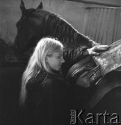 Lata 60., okolice Piotrkowa Trybunalskiego, Polska.
Obóz jeździecki. Kobieta przygotowuje konia do jazdy.
Fot. Irena Jarosińska, zbiory Ośrodka KARTA