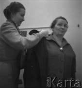 Lata 50., Warszawa, Polska.
Salon Cepelii przy ul. Rutkowskiego (obecnie Chmielna). Kobieta podczas mierzenia płaszcza. 
Fot. Irena Jarosińska, zbiory Ośrodka KARTA