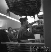 Lata 50., Warszawa, Polska.
Salon Cepelii przy ul. Rutkowskiego (obecnie Chmielna). Sprzedawczyni wyciąga towar z koszyka.
Fot. Irena Jarosińska, zbiory Ośrodka KARTA