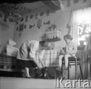 1961, Kadzidło, Polska.
Wnętrze chaty. Kobieta i dziecko. Ozdoby na ścianie - wycinanki kurpiowskie.
Fot. Irena Jarosińska, zbiory Ośrodka KARTA
