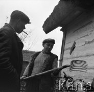 Lata 60., Bohoniki koło Sokółki, Polska.
Mężczyźni przy drewnianej chacie krytej strzechą. 
Fot. Irena Jarosińska, zbiory Ośrodka KARTA