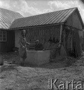 Lata 50. lub 60., okolice Krakowa, Polska.
Wieś. Kobieta i mężczyzna przed studnią koło domu. 
Fot. Irena Jarosińska, zbiory Ośrodka KARTA