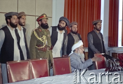 1992, Kabul, prowincja Kabul, Afganistan.
Konferencja prasowa afgańskiego polityka i przywódcy Sibghatullaha Modżaddediego (w białym turbanie). Od 28 kwietnia do 28 czerwca 1992 Modżaddedi pełnił funkcję tymczasowego prezydenta Afganistanu. Objął urząd po wycofaniu się wojsk radzieckich z Afganistanu, wkroczeniu  mudżahedinów do Kabulu i upadku wspieranych przez Sowietów komunistycznych rządów prezydenta Mohammada Nadżibullaha.
Fot. Irena Jarosińska, zbiory Ośrodka KARTA