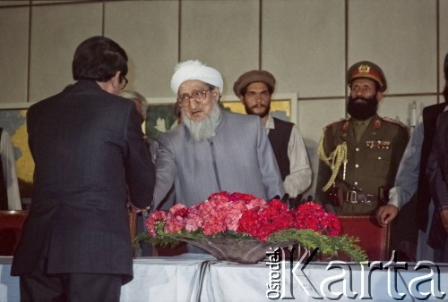 1992, Kabul, prowincja Kabul, Afganistan.
Konferencja prasowa afgańskiego polityka i przywódcy Sibghatullaha Modżaddediego (w białym turbanie). Od 28 kwietnia do 28 czerwca 1992 Modżaddedi pełnił funkcję tymczasowego prezydenta Afganistanu. Objął urząd po wycofaniu się wojsk radzieckich z Afganistanu, wkroczeniu  mudżahedinów do Kabulu i upadku wspieranych przez Sowietów komunistycznych rządów prezydenta Mohammada Nadżibullaha.
Fot. Irena Jarosińska, zbiory Ośrodka KARTA