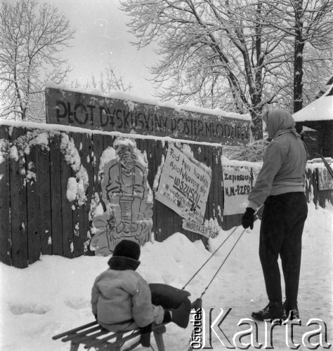 Listopad-grudzień 1956, Zakopane, woj. krakowskie, Polska.
Kobieta z dzieckiem oglądają płot z plakatami wywieszonymi przez członków Rewolucyjnego Związku Młodzieży.
Fot. Irena Jarosińska, zbiory Ośrodka KARTA