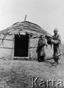 1913, Mongolia.
Mongołka lub Mongoł i chłopak obok wejścia do jurty. 
Zdjęcie pochodzi z albumu z podróży Zdzisława i Konstancji Poklewskich-Koziełł, Janusza i Natalii Łosiów oraz Stanisława i Julii Rosenwerthów do Mongolii w 1913 roku. 
Fot. Zdzisław Poklewski-Koziełł, zbiory Ośrodka KARTA, przekazała Hanna Kunachowicz