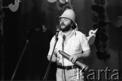Kwiecień 1983, Inowrocław, woj. bydgoskie, Polska.
Eliminacje do XIX Festiwalu Piosenki Radzieckiej. Na scenie jeden z uczestników eliminacji w hełmie korkowym. W dłoni trzyma lunetę.
Fot. Romuald Broniarek, zbiory Ośrodka KARTA