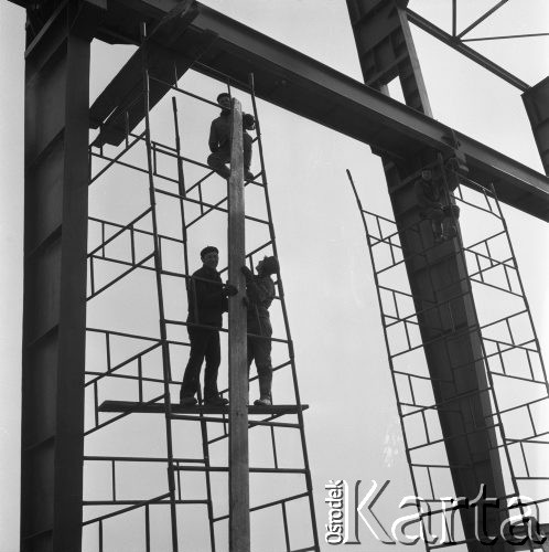 Marzec 1975, Dąbrowa Górnicza, woj. Katowice, Polska.
Budowa Huty Katowice, wznoszenie stalowej konstrukcji hali produkcyjnej, robotnicy w kaskach ochronnych na rusztowaniu.
Fot. Romuald Broniarek/KARTA
