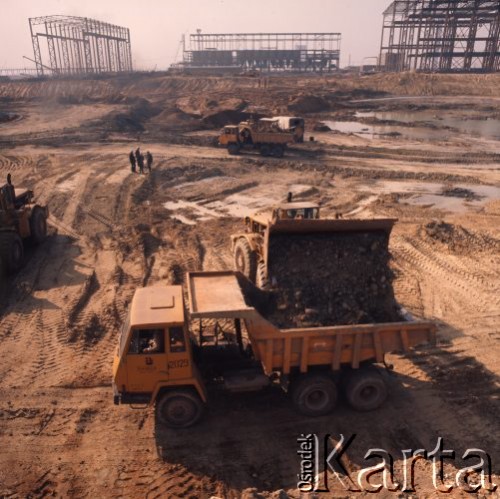 Marzec 1975, Dąbrowa Górnicza, woj. Katowice, Polska.
Budowa Huty Katowice, koparka ładująca ziemię na ciężarówkę.
Fot. Romuald Broniarek/KARTA
