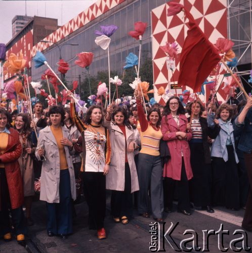 1.05.1975, Warszawa, Polska. 
Obchody święta 1 Maja, uczestnicy pochodu przechodzą ulicą Marszałkowską, na pierwszym planie dziewczyny z kwiatami z bibuły.
Fot. Romuald Broniarek/KARTA
