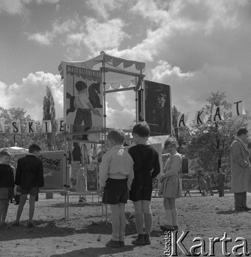 Maj 1956, Warszawa, Polska.
Dzieci oglądają plenerową wystawę plakatów filmowych, zorganizowaną podczas kiermaszu książki, z lewej plakat amerykańskiego filmu 