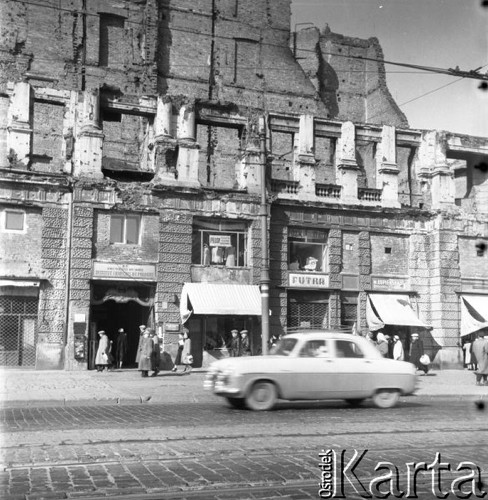 Lipiec 1956, Warszawa, Polska.
Aleje Jerozolimskie - sklepy w zniszczonym budynku, z lewej wejście do siedziby Instytuty Francuskiego. Na pierwszym planie samochód jadący ulicą.
Fot. Romuald Broniarek, zbiory Ośrodka KARTA