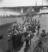 Lipiec 1957, Warszawa, Polska.
Warszawiacy na przystani nad Wisłą - kolejka do kasy dworca wodnego, w tle most średnicowy.
Fot. Romuald Broniarek, zbiory Ośrodka KARTA