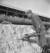 Wrzesień 1957, Warszawa, Polska.
Budowa Mostu Gdańskiego na filarach i z wykorzystaniem niektórych elementów konstrukcyjnych zburzonego Mostu przy Cytadeli. Robotnik ze świdrem.
Fot. Romuald Broniarek, zbiory Ośrodka KARTA