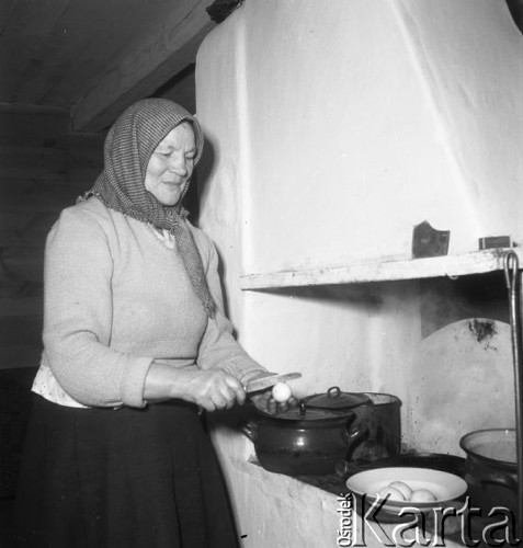 Styczeń 1958, Augustowo, pow. Bielsk-Podlaski, woj. Białystok, Polska.
Kobieta w chustce na głowie stoi przy piecu i rozbija jajka na jajecznicę.
Fot. Romuald Broniarek, zbiory Ośrodka KARTA