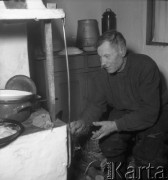 Styczeń 1958, Augustowo, pow. Bielsk-Podlaski, woj. Białystok, Polska.
Mężczyzna rozpala drewnem w piecu.
Fot. Romuald Broniarek, zbiory Ośrodka KARTA