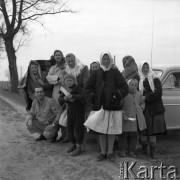 Kwiecień 1958, Jackowice, woj. Łódź, Polska.
Grupa wiejskich kobiet i dzieci na tle samochodu, w środku stoi chłopiec z chorągiewką.
Fot. Romuald Broniarek, zbiory Ośrodka KARTA
