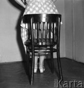 Czerwiec 1958, Warszawa, Polska.
Kobieta zakładająca spódnicę, na pierwszym planie drewniane krzesło.
Fot. Romuald Broniarek, zbiory Ośrodka KARTA