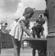 Czerwiec 1958, Warszawa, Polska.
Dwie dziewczynki przy studni na Rynku Nowego Miasta, w tle fragment ulicy Freta.
Fot. Romuald Broniarek, zbiory Ośrodka KARTA