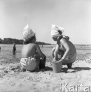 Lipiec 1958, Warszawa, Polska.
Warszawiacy na plaży nad Wisłą, dwójka dzieci w chusteczkach na głowach robi babki z piasku.
Fot. Romuald Broniarek, zbiory Ośrodka KARTA