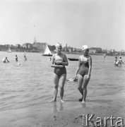 Lipiec 1958, Warszawa, Polska.
Warszawiacy na plaży nad Wisłą - na pierwszym planie dwie kobiety w strojach kąpielowych, w tle żagłówki na rzece oraz Pałac Kultury i Nauki.
Fot. Romuald Broniarek, zbiory Ośrodka KARTA