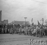 1.05.1959, Warszawa, Polska. 
Obchody święta 1 Maja, ulica Marszałkowska, uczestnicy defilady niosą transparenty Związku Młodzieży Socjalistycznej, flagi PRL i ZSRR, na drugim planie fragment trybuny honorowej, siódmy od lewej stoi premier Józef Cyrankiewicz, za nim kolejno: I sekretarz KC PZPR Władysław Gomułka, prezydent Indonezji Ahmed Sukarno, przewoniczący Rady Państwa Aleksander Zawadzki, w tle fragment Pałacu Kultury i Nauki. 
Fot. Romuald Broniarek, zbiory Ośrodka KARTA