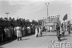 1.05.1959, Warszawa, Polska. 
Obchody święta 1 Maja, pochód przechodzący ulicą Marszałkowską, na pierwszym planie dziennikarze robiący zdjęcia i hutnicy niosący transparent z napisem propagandowym 