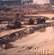 Marzec 1975, Dąbrowa Górnicza, woj. Katowice, Polska.
Budowa Huty Katowice, spychacz i ciężarówki jadące utwardzoną drogą przez plac budowy.
Fot. Romuald Broniarek/KARTA
