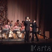 Kwiecień 1975, Warszawa, Polska.
Dni Kultury Radzieckiej, koncert galowy w Sali Kongresowej Pałacu Kultury i Nauki, na pierwszym planie piosenkarz z mikrofonem, w tle orkiestra.
Fot. Romuald Broniarek/KARTA
