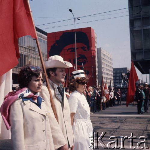 1.05.1975, Warszawa, Polska. 
Obchody święta 1 Maja, uczestnicy pochodu przechodzą ulicą Marszałkowską, na pierwszym planie hutnik z biało-czerwoną flagą, pielęgniarka i kobieta w białym żakiecie. W tle wisi portret Włodzimierza Lenina.
Fot. Romuald Broniarek/KARTA

