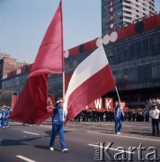 1.05.1975, Warszawa, Polska. 
Obchody święta 1 Maja, uczestnicy pochodu przechodzą ulicą Marszałkowską, na pierwszym planie dwaj mężczyźni z flagami.
Fot. Romuald Broniarek/KARTA
