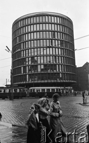 Maj 1959, Poznań, Polska.
Kobiety chroniące się przed deszczem pod folią, w tle Dom Towarowy 