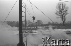 Luty 1976, Polska.
Słuchacze Wyższej Oficerskiej Szkoły Wojsk Zmechanizowanych we Wrocławiu podczas ćwiczeń na poligonie. Żołnierz przechodzi przez rzekę po rozpiętych linach.
Fot. Romuald Broniarek/KARTA