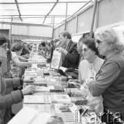 Maj 1976, Warszawa, Polska.
Kiermasz Książki przed Pałacem Kultury i Nauki, kupujący przy stoisku z książkami, na pierwszym planie trzy kobiety w przeciwsłonecznych okularach.
Fot. Romuald Broniarek/KARTA