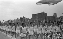 22.07.1959, Warszawa, Polska.
Uroczyste obchody piętnastolecia PRL z udziałem Nikity Chruszczowa, I sekretarza KC KPZR. Młodzi mężczyźni w strojach sportowych przechodzą przed trybuną honorową wiwatując kwiatami.
Fot. Romuald Broniarek/KARTA