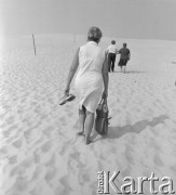 Sierpień 1976, Łeba, Polska.
Turyści na wydmach w okolicach Łeby, na pierwszym planie kobieta idąca boso i trzymająca klapki w ręku.
Fot. Romuald Broniarek/KARTA
