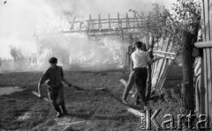 Sierpień 1959, Sandomierz, Polska.
Płonący budynek, na pierwszym planie mężczyźni biorący udział w akcji ratunkowej niszczą płot, żeby zapobiec rozprzestrzenianiu się pożaru.
Fot. Romuald Broniarek/KARTA