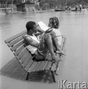 Sierpień 1962, Sandomierz, Polska. 
Międzynarodowy Obóz Studencki, czarnoskóry chłopak i dziewczyna siedzą na ławce stojącej na placu zalanym wodą.
Fot. Romuald Broniarek/KARTA