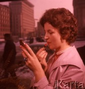 Styczeń 1963, Warszawa, Polska.
Sklep kosmetyczny przy ulicy Kruczej, ekspedientka demonstruje czerwoną szminkę.
Fot. Romuald Broniarek/KARTA