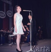 Listopad 1970, Warszawa, Polska.
Sala Kongresowa w Pałacu Kultury i Nauki. Laureatka (prawdopodobnie Bożena Adamek) VI Konkursu Piosenki Radzieckiej w Zielonej Górze  w czasie koncertu z okazji 53. rocznicy Wielkiej Socjalistycznej Rewolucji Październikowej. Orkiestrą dyryguje Stefan Rachoń.
Fot. Romuald Broniarek, zbiory Ośrodka KARTA.
